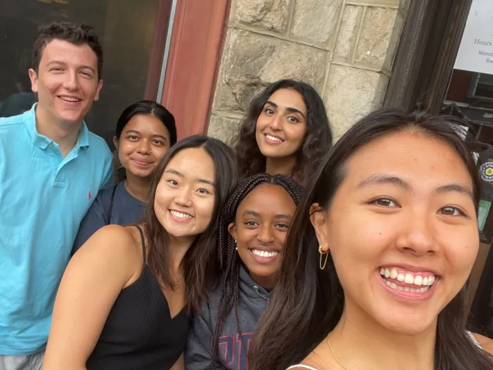 Six young people smiling together in a group selfie